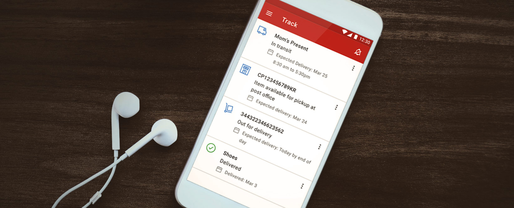 A cellphone is used to track multiple shipments in the Canada Post app. Earbuds rest beside the phone.